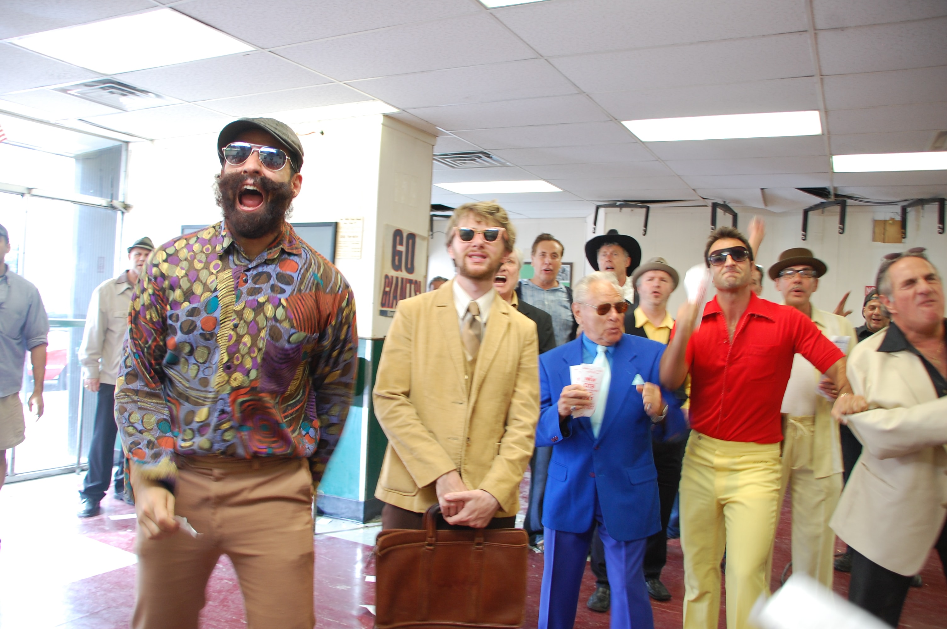 A crowd of men in retro 1970s clothing reacting in a large room