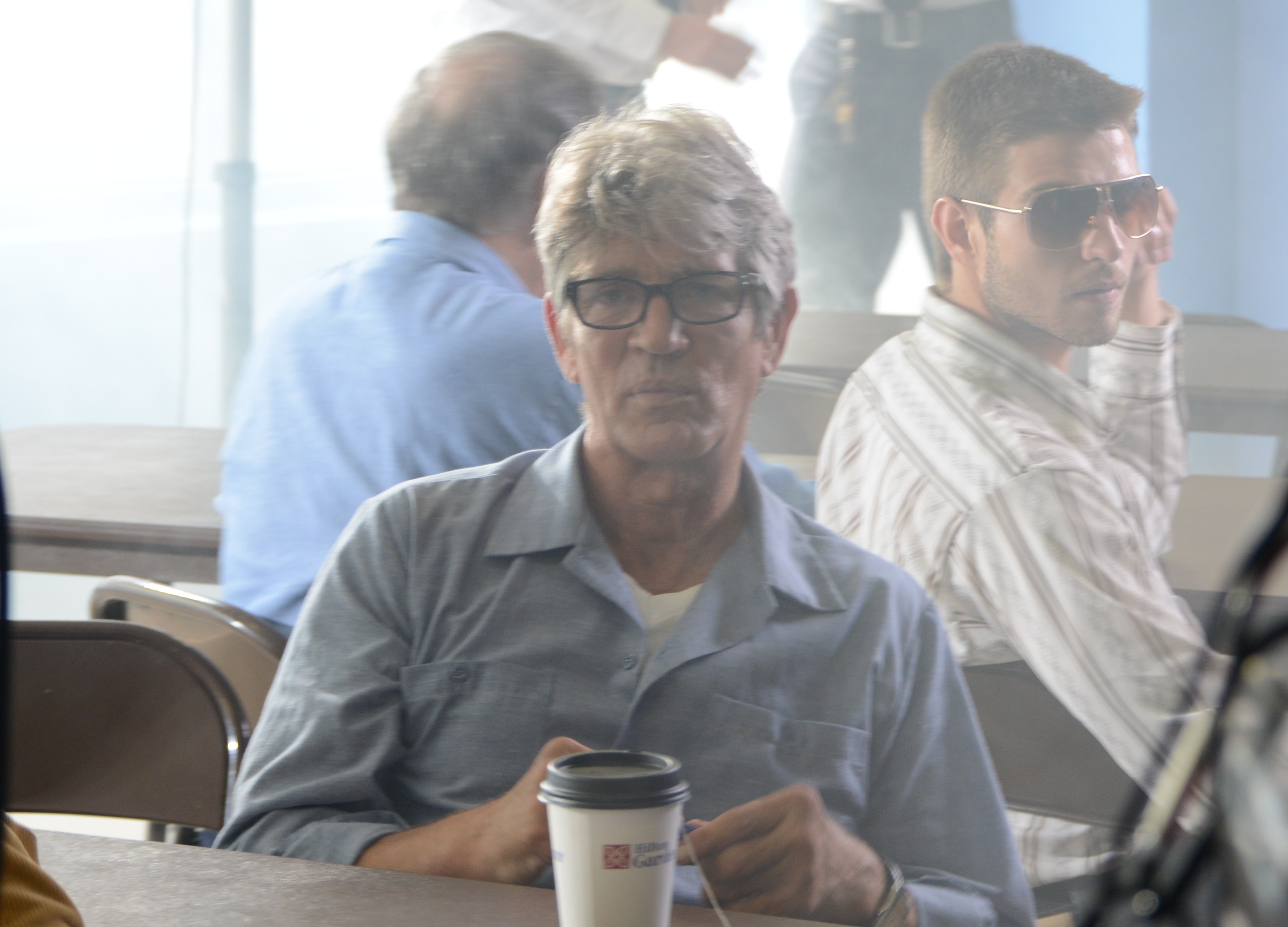 A man with glasses holds a coffee cup at a diner table