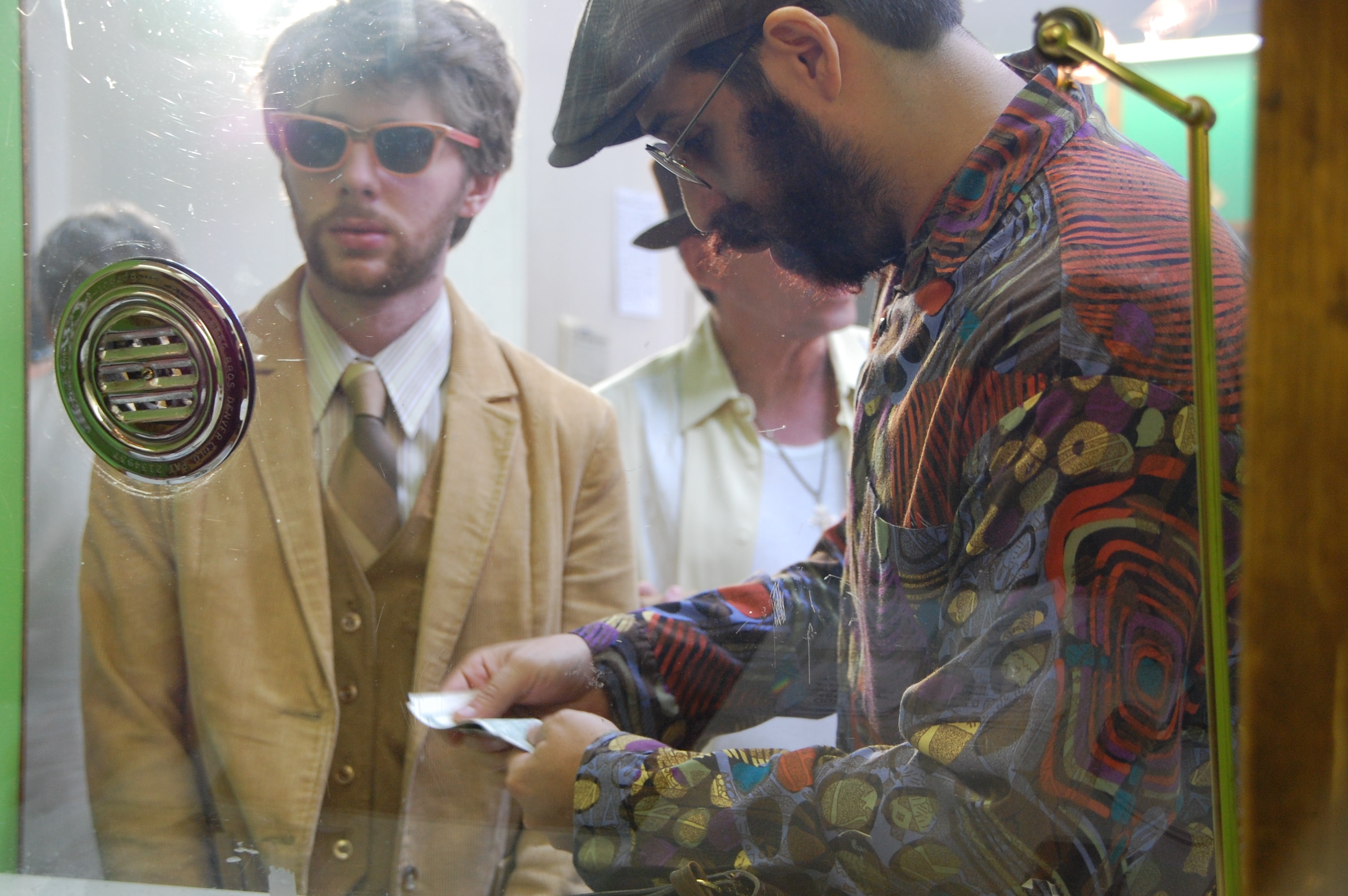 Two men at a ticket window, one counting money